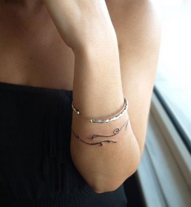 apyrankės tatuiruotės moteris su gėlių raštais, minimalistinė riešo tatuiruotės idėja su tikra apyranke