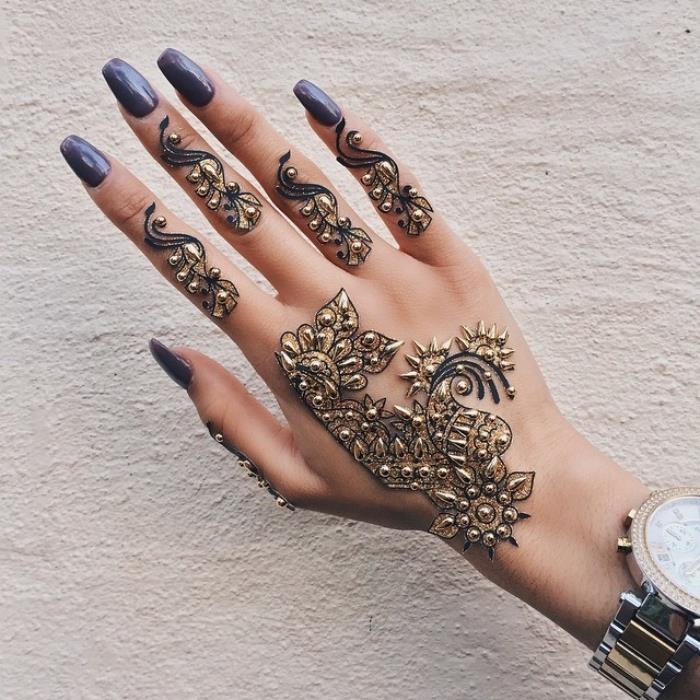 črna kana, body art na rokah z obliko črne kane in majhnimi zlatimi čepi, manikura z dolgimi nohti