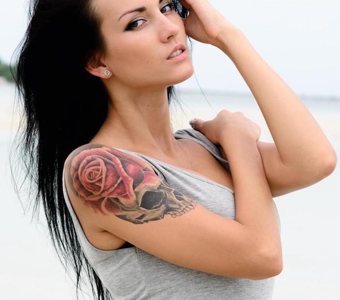 rjavolaska z tetovažo lobanje v črnem senčenju in rdečo vrtnico na rami kot tetovažo roke