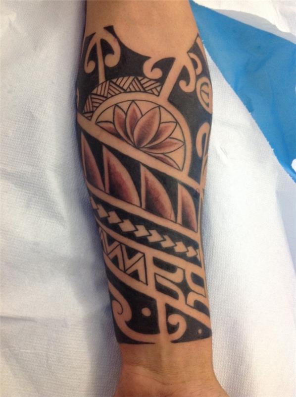 model tetovaže, rdeča in črna oblika na roki z obliko lotosa ter geometrijskimi in plemenskimi vzorci