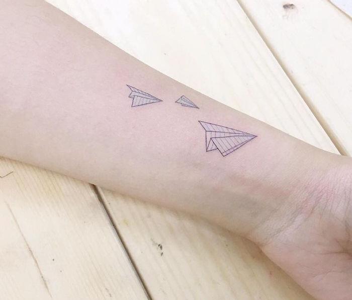 tetovaže papirnatih letal v modrem črnilu na podlakti