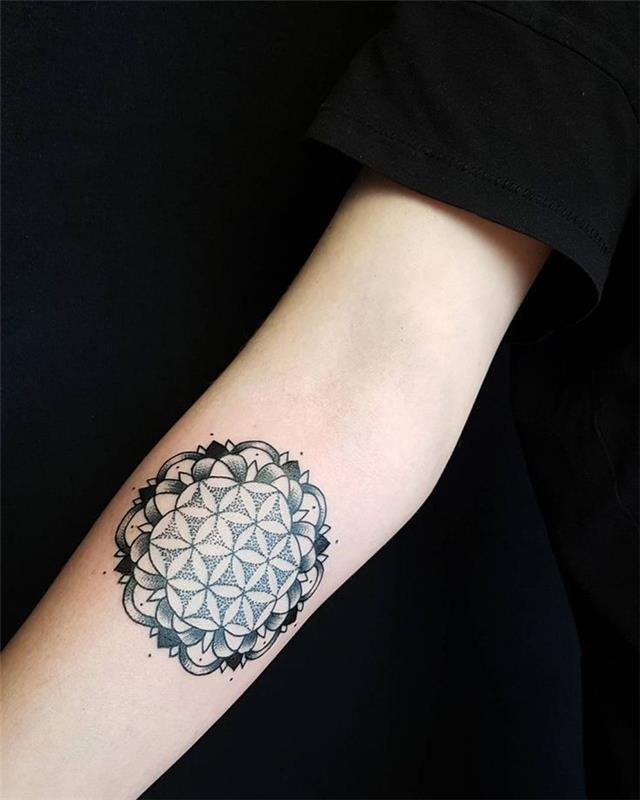 „Tatuaggi geometrici e un disegno con cerchi and petali di fiori sul braccio di una ragazza“
