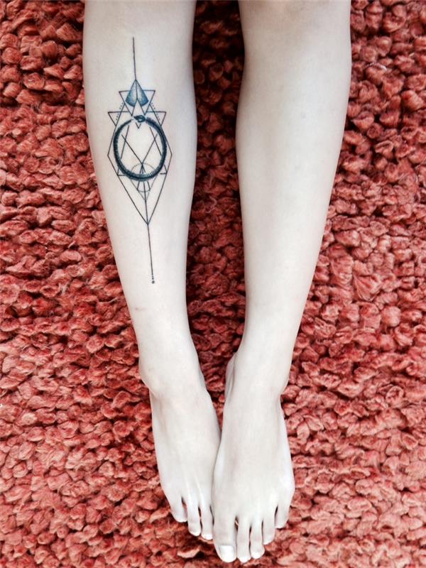 simbolična navpična tetovaža z geometrijsko obliko in ouroborosom v notranjosti, narejena na nogi