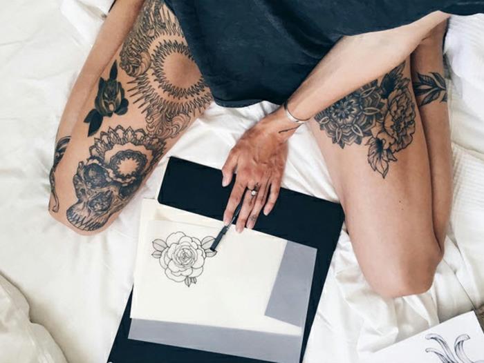 tattoo-fiore-idea-diversi-disegni-cosce-ragazza-seduta-letto-disegna-peonia