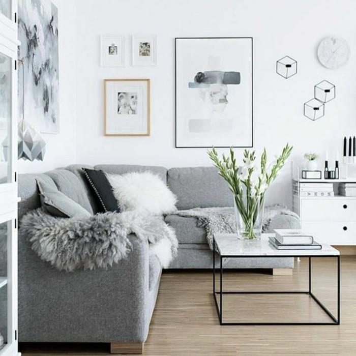 Salotto con divano grigio, soggiorno con pareti bianche, tavolino basso di colore bianco lucido