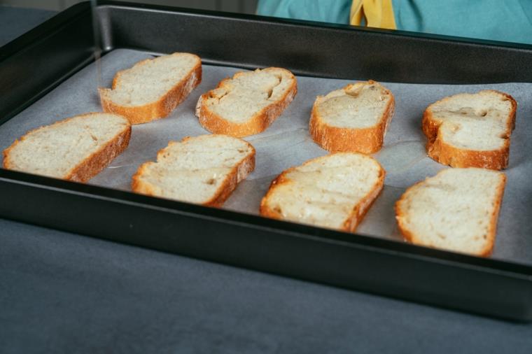 Fette di pane con filo di olio in teglia, ricetta hummus, crostini di pane in una teglia da forno