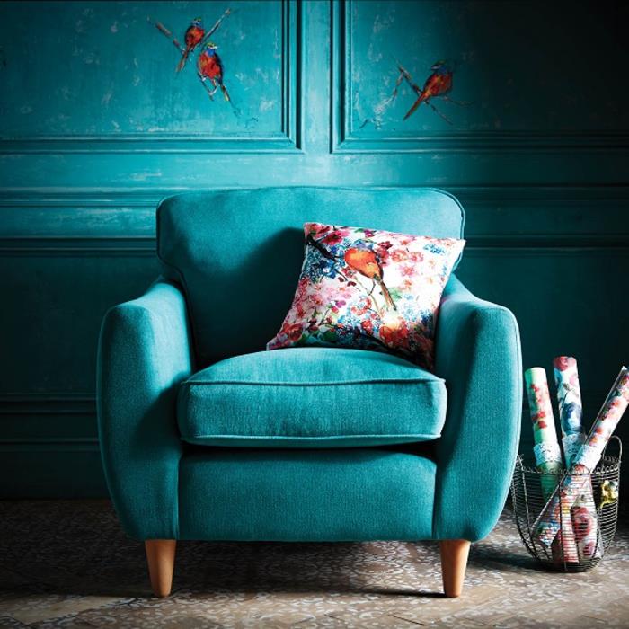 elegantiškas žalsvai mėlynas fotelis, suporuotas su gėlių rašto pagalve