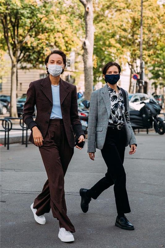 žiemos tendencija 2021 m. du žmonės su kaukėmis per mados savaitę rudas kostiumas ir balti sportbačiai