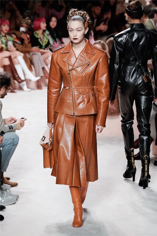 2021 m. žiemos tendencija gigi hadid apsirengusi odiniu rudu sijonu ir švarku