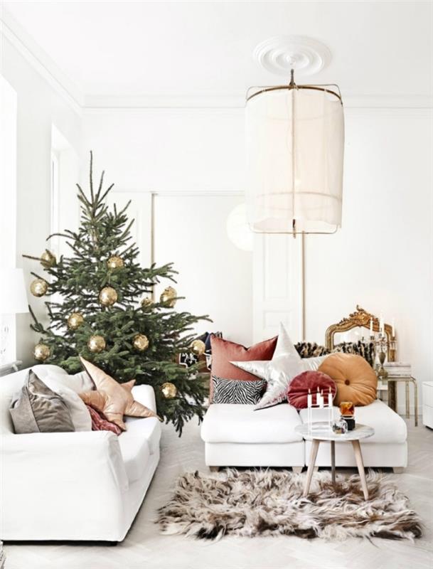 beyaz mobilyalarla döşenmiş beyaz bir odada altın toplarla süslenmiş doğal Noel ağacı resmi