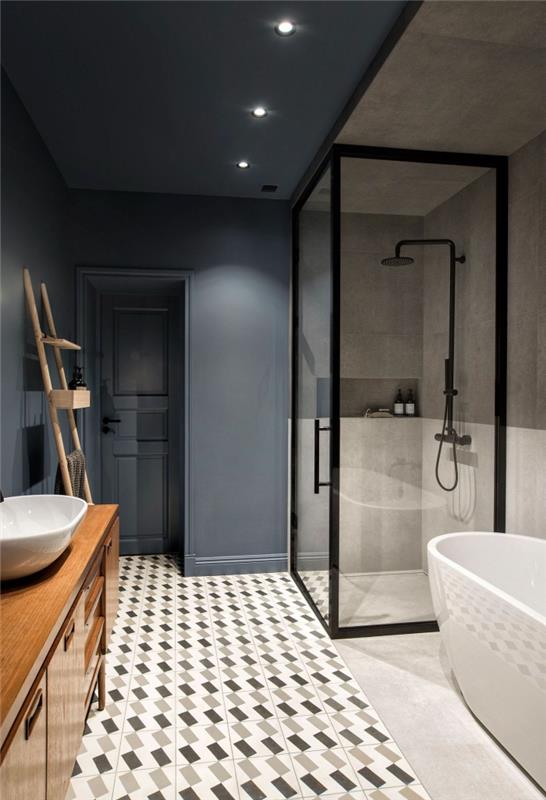 Itališkas vonios kambarys su grafine cemento plytelių išvaizda, vizualiai atskiriančia erdvę į dvi dalis