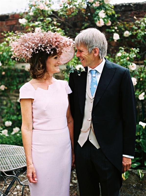 vestuvinės suknelės idėja moteriai 60 metų nuotakos mamai, rožinė suknelė su tiesiu kirpimu ir trumpomis rankovėmis su asimetrine iškirpte, kartu su tos pačios spalvos vestuvine kepure