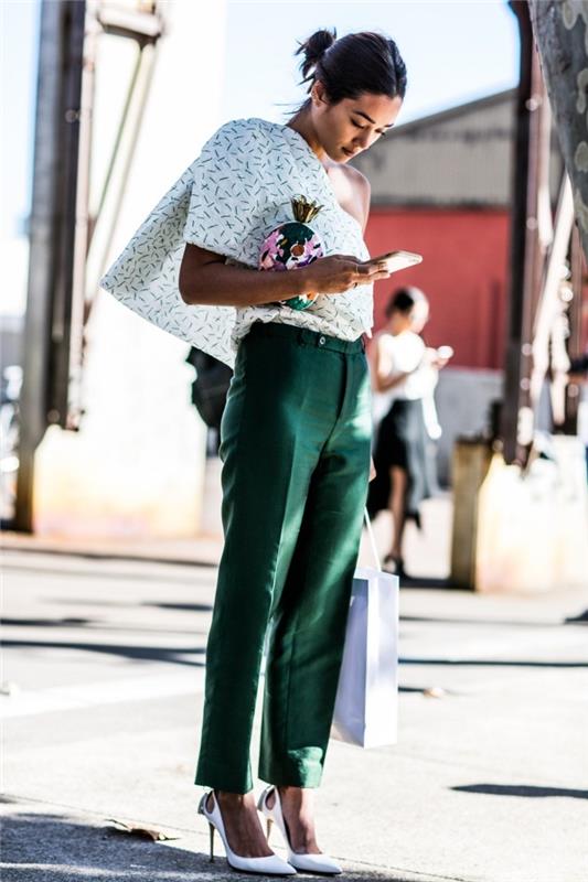 model hlač z visokim pasom v temno zeleni barvi v kombinaciji z belo bluzo z asimetričnim ovratnikom in belimi čevlji