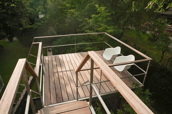 dvignjena lesena terasa, beli stoli, pogled na vrt, lesena ograja, leseno stopnišče