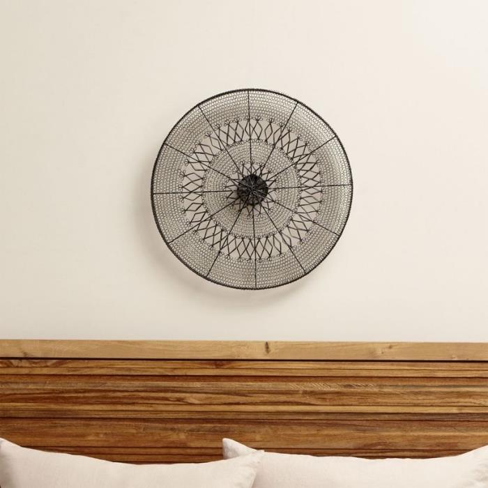 miegamojo dekoras su rudos medienos galvūgaliu ir ant baltos sienos kabantis mandalos dizaino geležies kūrinys