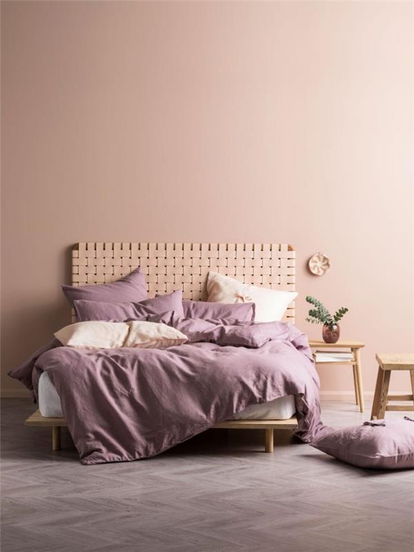 gri zeminli minimalist bir yatak odasında soluk pembe boya, dokuma bitkisel elyaftan orijinal başlık modeli