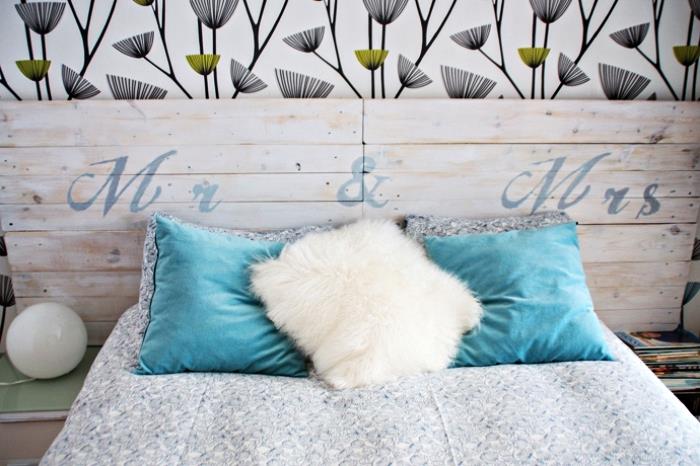 naredite vzglavje, leseno posteljo z belo in temno modro odejo, okrašeno s turkiznimi in belimi blazinami