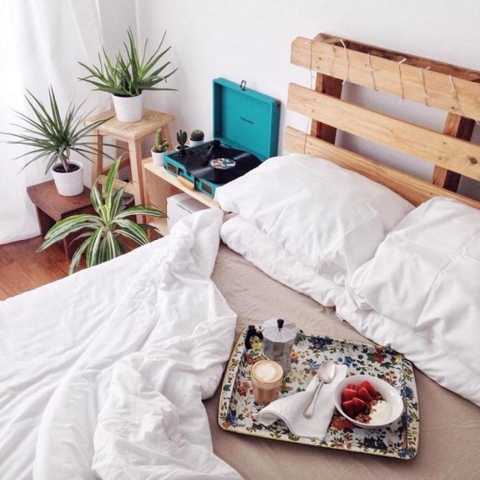 retro country chic spalnica, bela in siva posteljna postelja, vzglavnik DIY v paleti iz svetlega lesa, zelene rastline