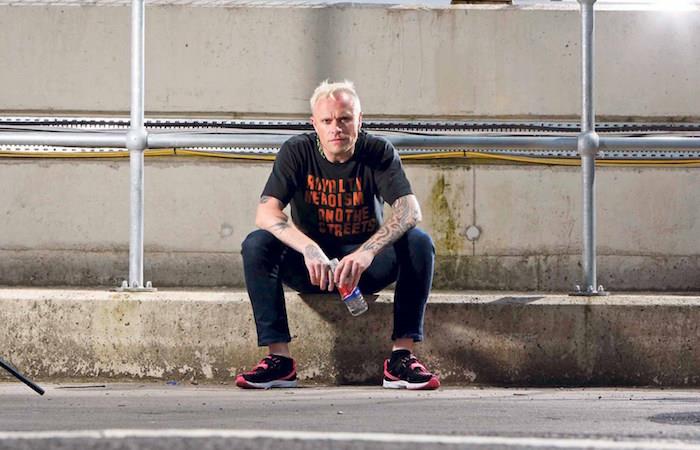 Keith Flint'in asılarak ölüm nedenlerinin açıklandığı haber makalesi için kaldırımda gündelik kıyafetleriyle otururken çekilmiş fotoğrafı