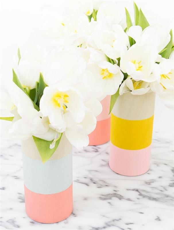 vaze za rože, pobarvane v pastelno roza, bledo modro in živo rumeno, komplet treh, postavljenih na marmorno površino in vsebuje bele tulipane