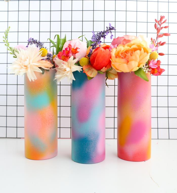beyaz yüzeye yerleştirilmiş çok renkli sprey boyalı vazolar, içinde çiçek buketleri, düşünceli yılbaşı hediyeleri