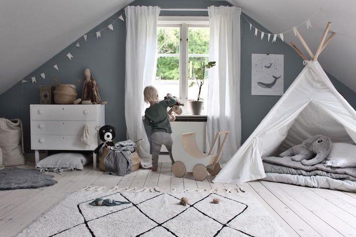 Otrok se igra s temi lesenimi igračami, skandinavska ideja dekoriranja otroške sobe s teepeejem, kakšne barve s sivo, sivo zasnovo spalnice
