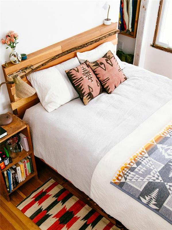 miegamojo dekoras su etniniu audiniu, actekų pagalvėlės rožinės ir juodos spalvos, prie lovos su knygomis