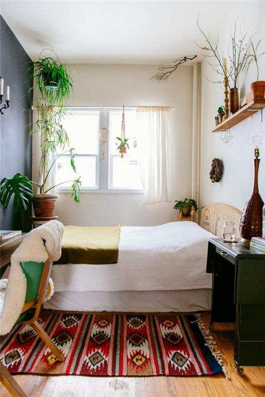 etninis audinys, du nedideli rašomieji stalai miegamajame, medinė sienų apdaila ir žali augalai