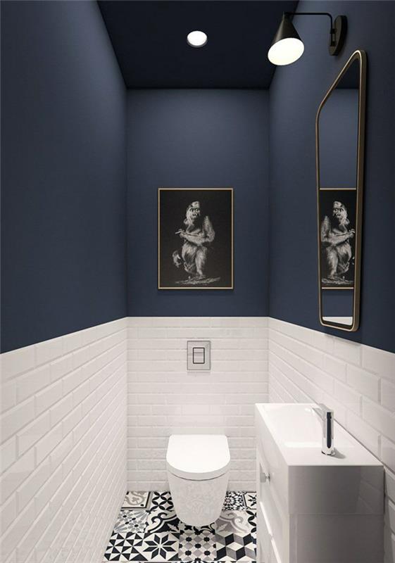vonios reikmenys mėlynos ir baltos spalvos, baltos metro plytelės, įrėmintas veidrodis, cemento plytelių grindys