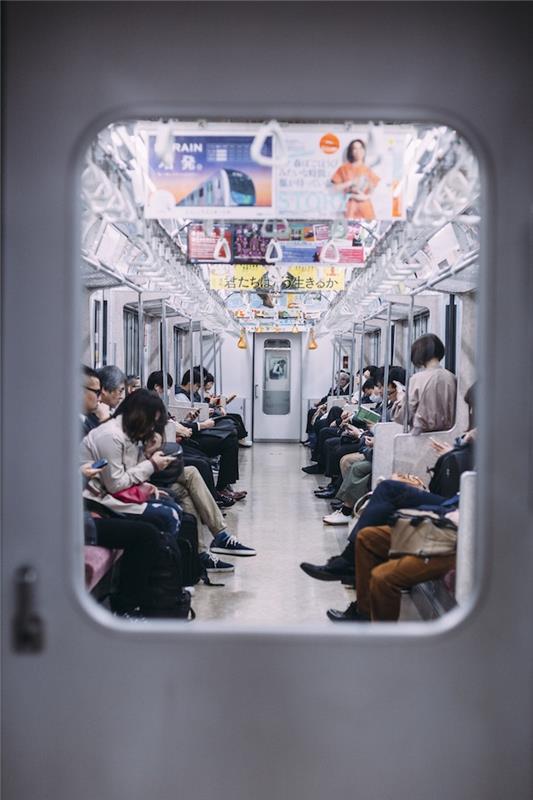 V podzemni železnici vsi s svojimi mobilnimi telefoni mestna pokrajina, azijska pokrajina, japonska pokrajina, urbana fotografija