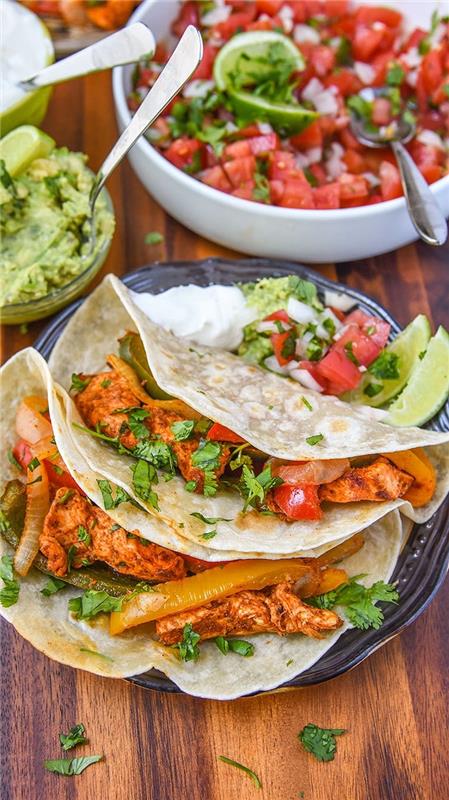 Tortilje con carne, ciotola con insalata di pomodoro, ciotola con guacamole, la cena di stasera