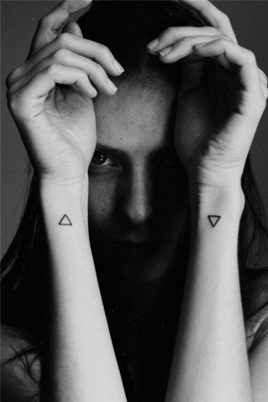 maži trikampiai riešo tatuiruotė, ant abiejų rankų, moteris abiem rankomis, priešais veidą, mažos derančios tatuiruotės