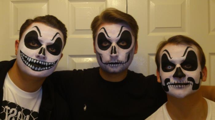 Helovino vyro makiažas, dideli kontūrai aplink akis, nupiešti antakiai ant kaktos, trys draugai, pasipuošę Helovino makiažu