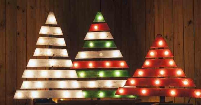 Kalėdų eglutės padėkluose, nudažytos balta žalia ir raudona spalvomis ir apšviestos mažomis lemputėmis