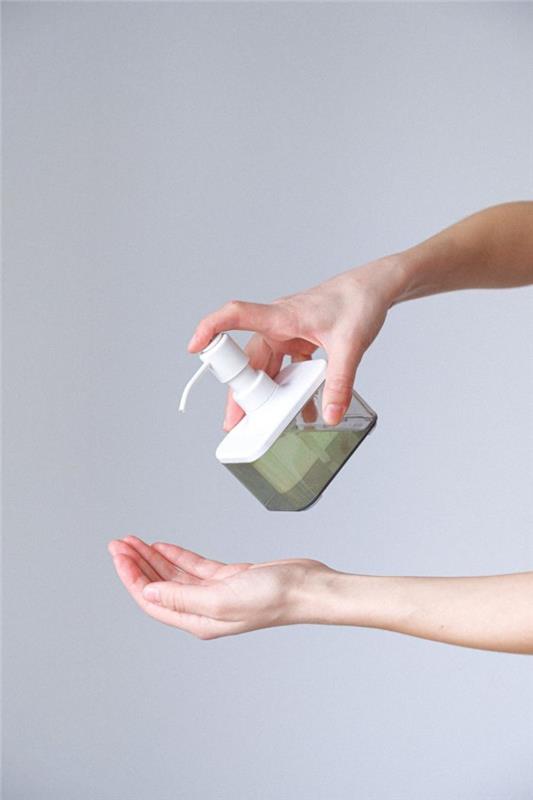 Donna che si versa del sapone sul palmo della mano, tutorial disinfettante mani