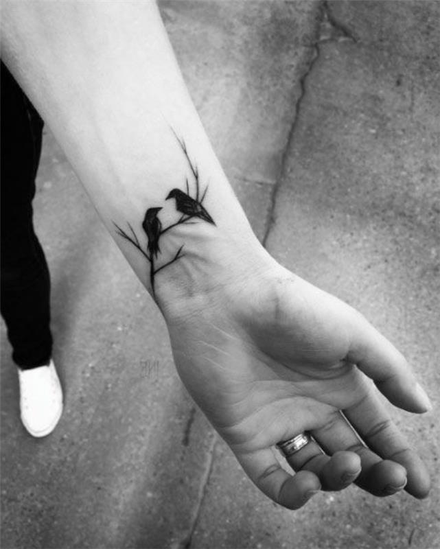 du paukščiai ant medžio šakos riešo tatuiruotės, žmogus dėvintis baltus sportbačius, mažos derančios tatuiruotės
