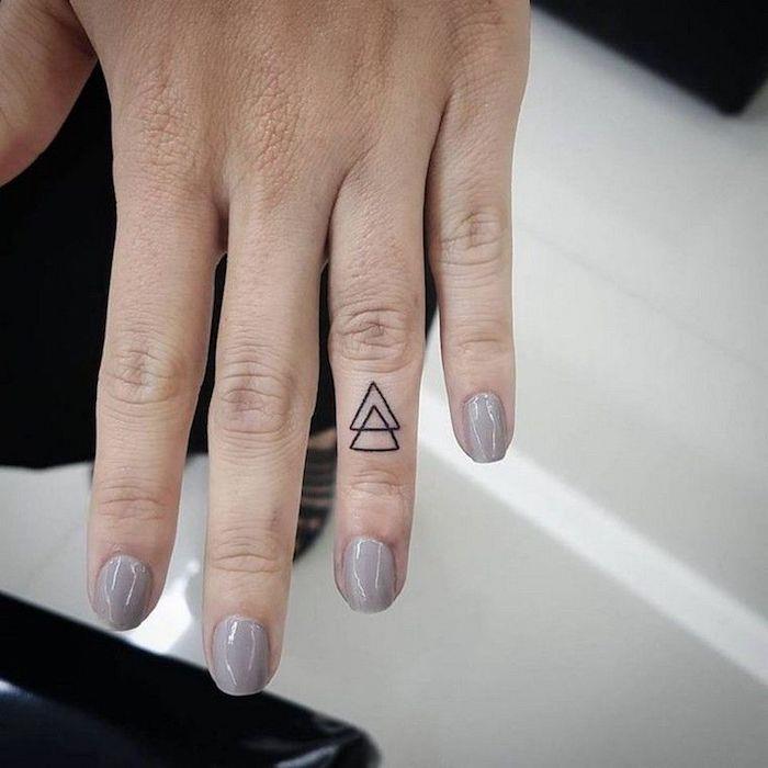 dva prepletena trikotnika, na prstancu, tetovaža prsta, roka s sivim lakom