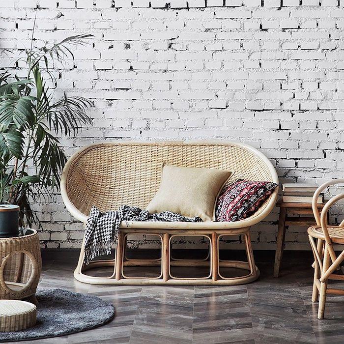 ovalo formos pinta sofa priešais plytų sieną šalia rotango kavos staliuko