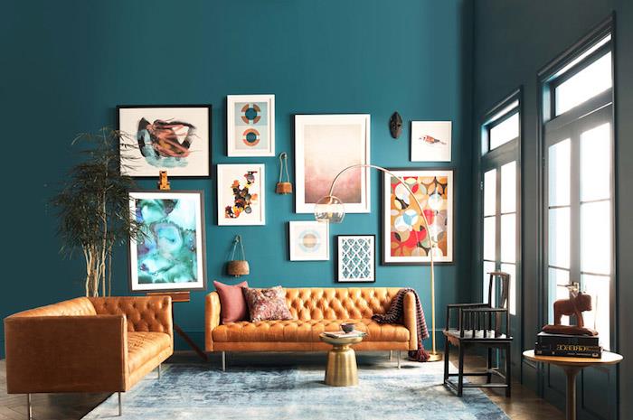 primer poceni kavča, dveh usnjenih zof na steni iz račje modrega ozadja, stenske dekoracije umetniških okvirjev, minimalistična mizica