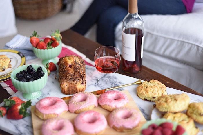 mažas gurmaniškas patiekalas su spurgomis, duona, vaisiais ir įvairiais skanėstais, butelis vyno, Valentino dienos dovanos idėja