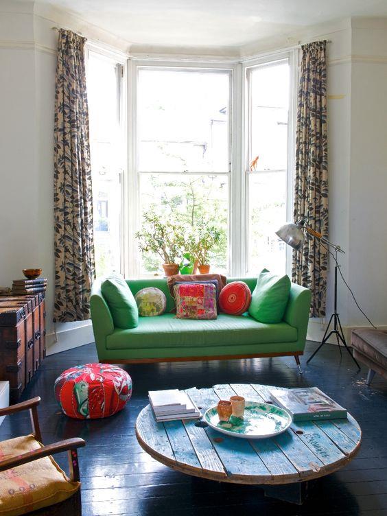 modern bir oturma odası düzenleme fikri, masa makarası, mavi ahşap tabla, lacivert parke, yeşil kanepe, rengarenk minderler