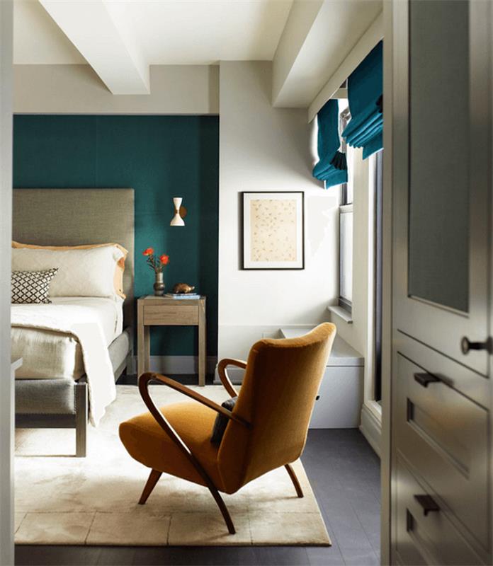 žalsvai mėlynos ir naftos spalvos suaugusiųjų miegamojo dekoravimo idėjos, beveik baltas kilimas, pilka lova, balta patalynė, garstyčių geltona kėdė, fono siena ir mėlynos žaliuzės