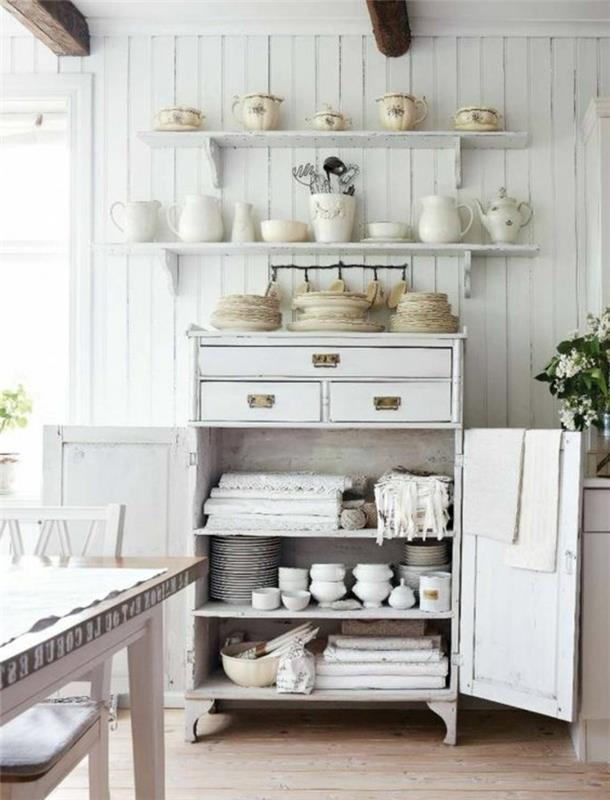 eleganten deželni dekor, beli predalnik, belo posodo, bele police, izpostavljeni tramovi, kmečka lesena miza