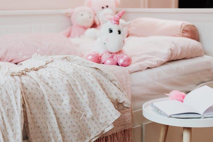 mažos mergaitės kambarys su suknele ir vienaragis peuche ant lovos