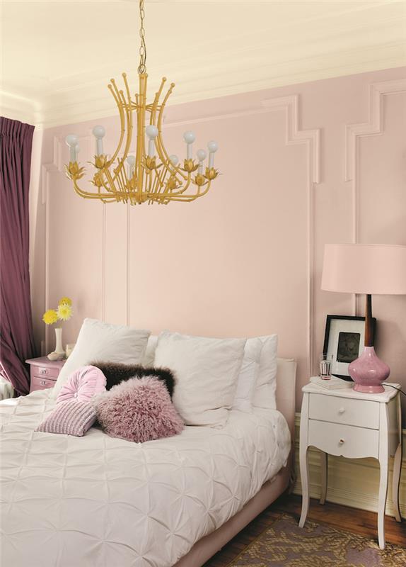 rožnato -bela spalnica z zlatim senčnikom, ki visi s stropa, in starimi rožnatimi zavesami