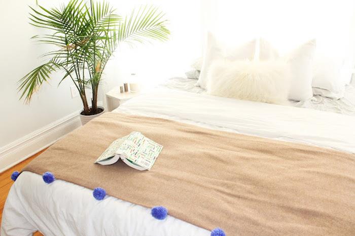 rudas lovos užtiesalas, papuoštas purpuriniais kutais, balta patalynė, pigi dovanos idėja