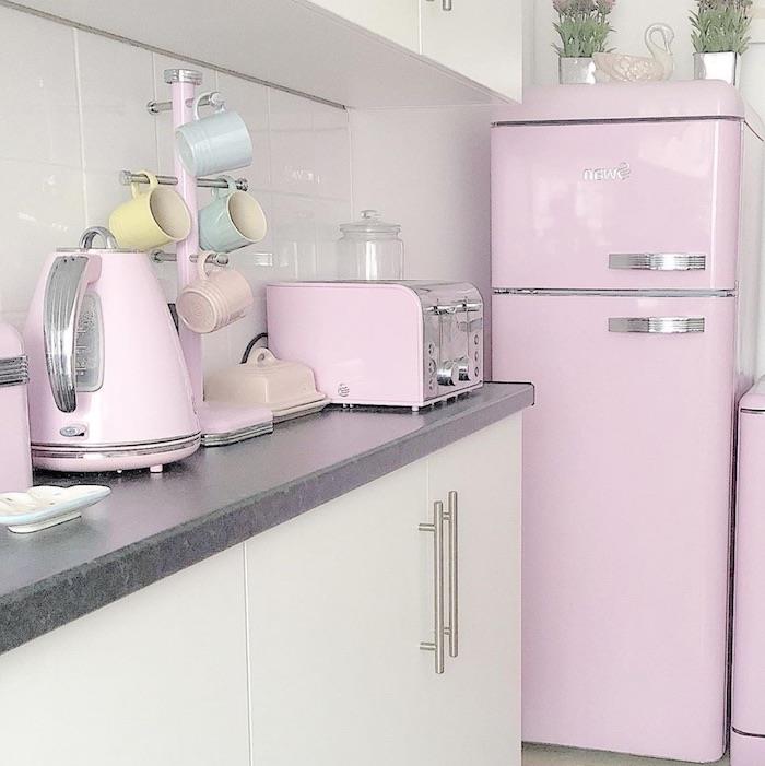 kuhinjo z belimi omarami in pastelno rožnatimi aparati ter hladilnikom