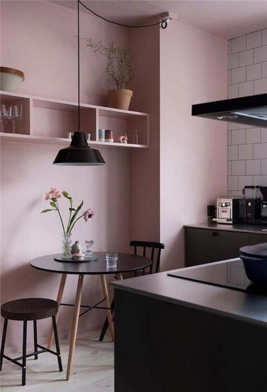 pastelno roza kuhinja na stenah ter črno pohištvo in aparati
