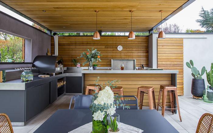 sodobna kuhinja na verandi z lesenimi površinami in bakrenim pohištvom z velikimi kaktusi v ozadju