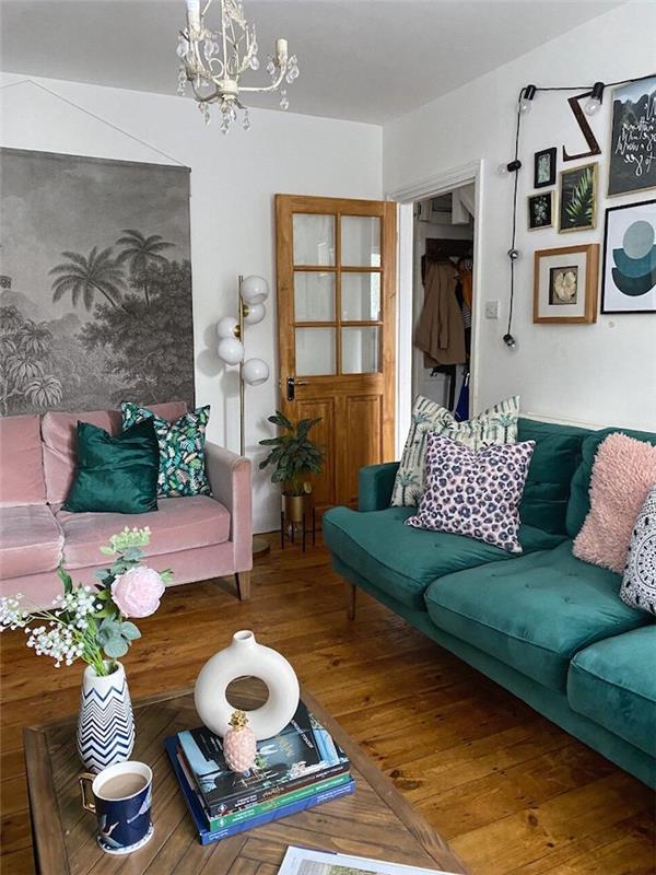 dnevna soba z dvema zelenima zofama in roza odtenkom, foto ozadje na steni in šopek na mizi